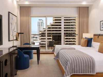 Nowoczesny pokój hotelowy z dwoma łóżkami, biurkiem i widokiem na miasto.