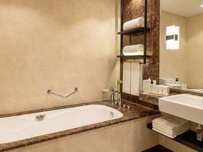 Nowoczesna łazienka z wanną, umywalką i ręcznikami w ciepłych kolorach.