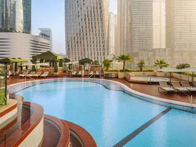 Basen na dachu z leżakami i widokiem na wieżowce w mieście.