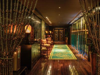 Luxe hotelgang met houten vloeren, elegante verlichting en decoratieve kralengordijnen.