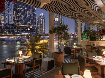 Wieczorny taras restauracyjny z widokiem na oświetlone miasto i rzekę