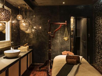 Luxe spa kamer met massagetafel, hanglampen, sierlijke spiegel en warme sfeerverlichting.