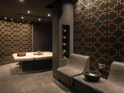 Moderne spa met twee ligstoelen en een ronde badkuip tegen patroonmuren.