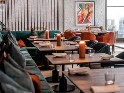 Modern eingerichteter Hotel- oder Restaurantbereich mit dunklen Tischen und grünen Sitzbänken.