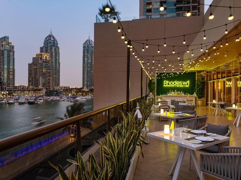 Gezellig dakterras met eetgedeelte bij schemering met uitzicht op de stad en lichtjes.