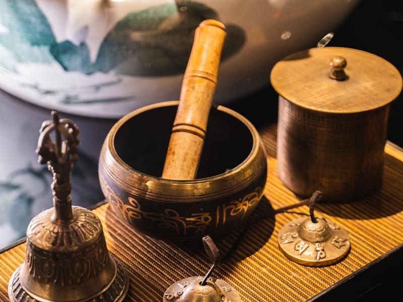 Een houten dienblad met een koperen bel, een koperen kom met houten stokje en een koperen pot.