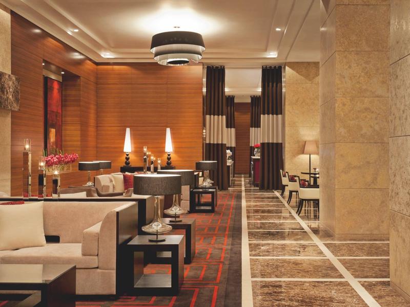 Luxe hotellobby met beige banken, warm licht en een marmeren vloerpand.