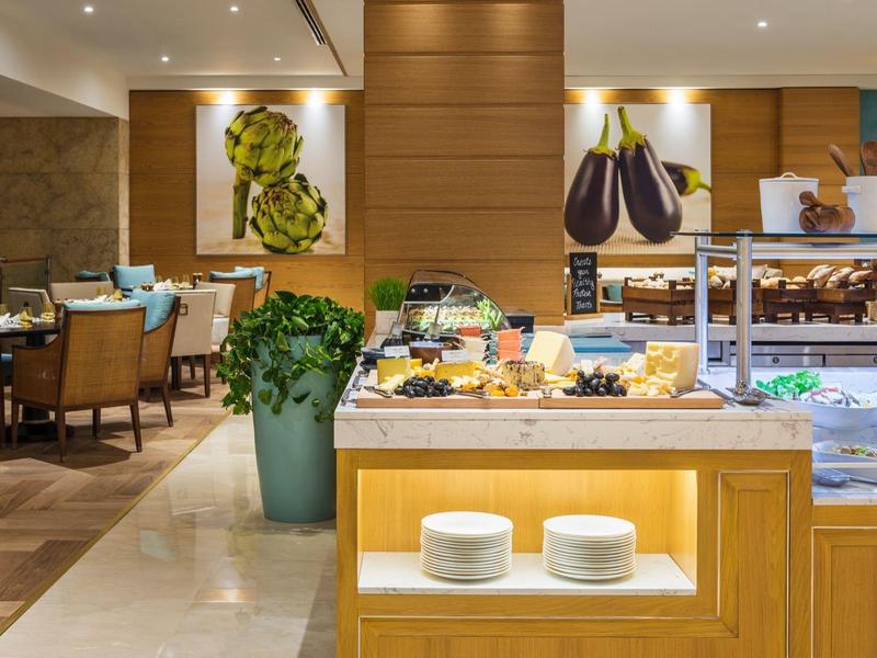 Goed verlichte hotelbuffet met verschillende eten opties en netjes opgestelde eettafels.