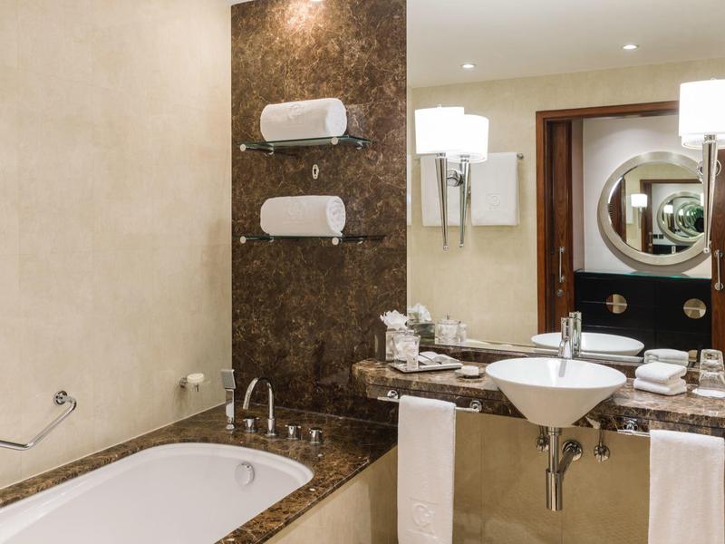 Moderne badkamer met bad, wastafel, spiegel en wandlampen.