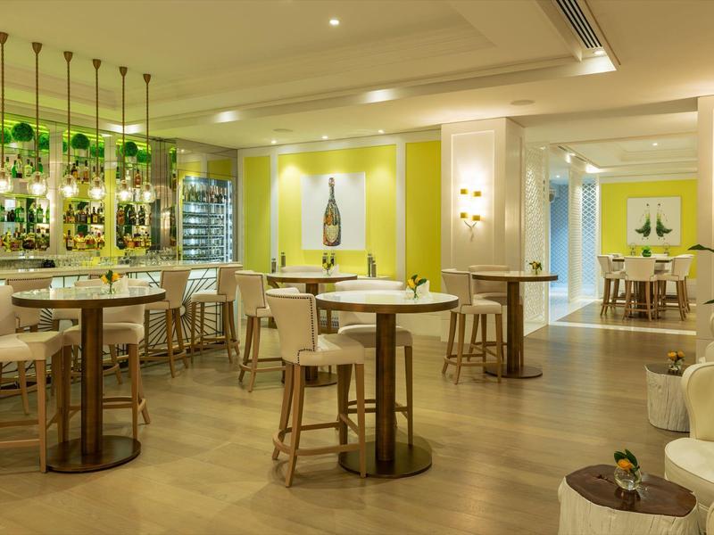 Moderne bar met houten krukken, groene accenten en warme verlichting in een hotel lounge.