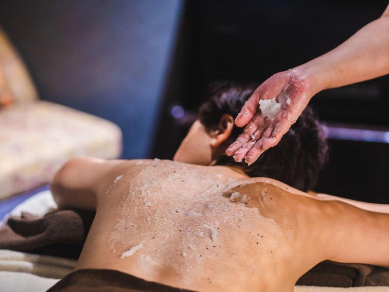 Persoon die een ontspannende rugmassage met scrub krijgt in een spa omgeving.