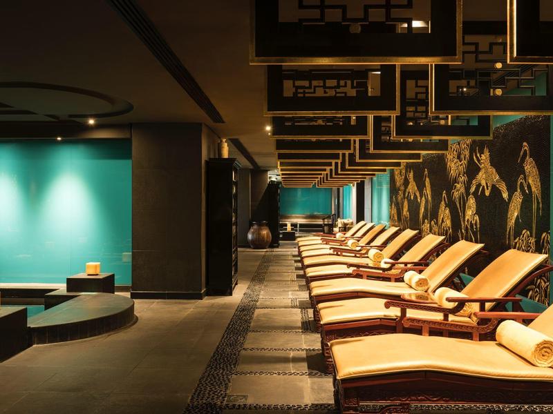 Ontspanningsruimte met ligstoelen en rustgevende verlichting langs een gang.