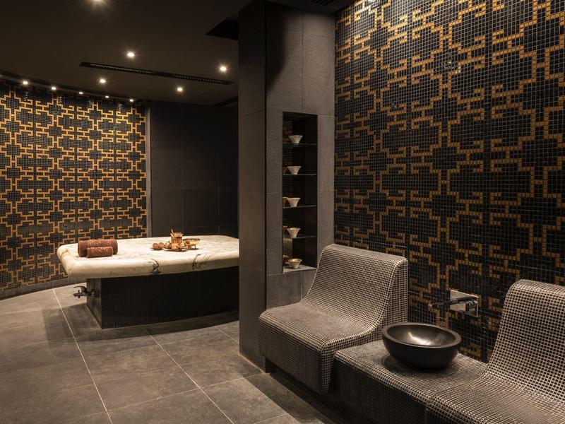 Moderne spa met twee ligstoelen en een ronde badkuip tegen patroonmuren.