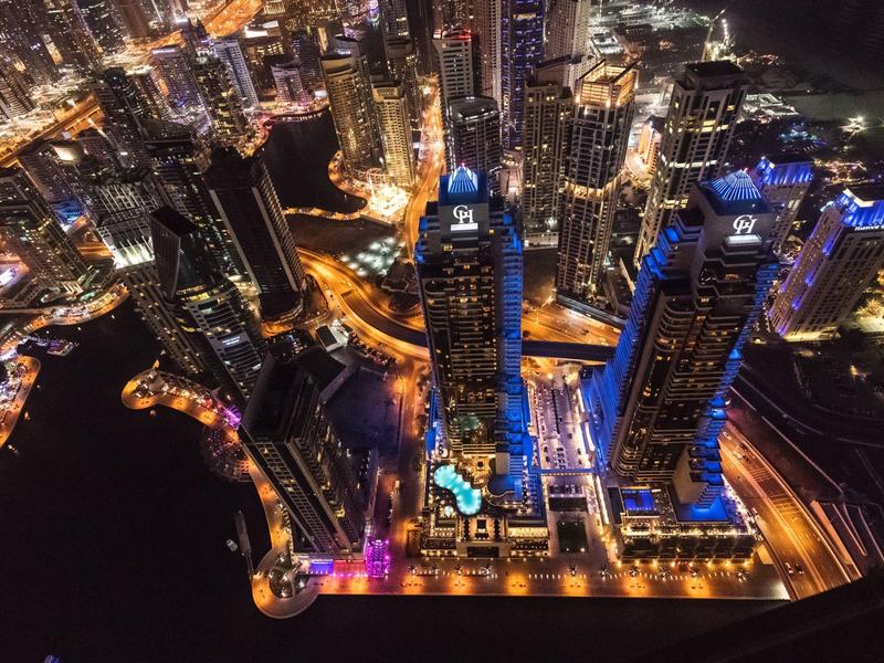 Luchtfoto van een fel verlichte stadshorizon 's nachts met hoge gebouwen en wegen.