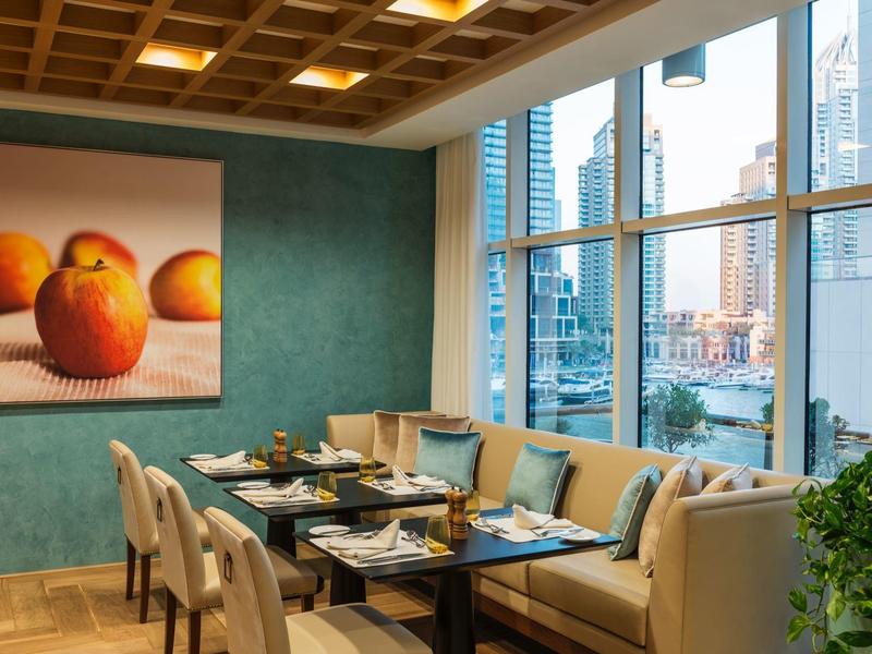 Gezellige eetruimte met uitzicht op de stad, perziken schilderij, beige stoelen en een hoekbank.