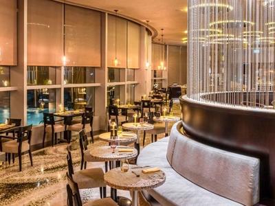 Modern hotel restaurant with elegant seating area and large windows at night.