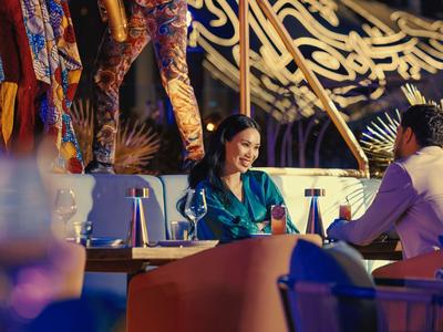 Coppia che gusta una cena in un ristorante elegante con decorazioni colorate.