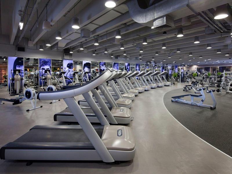 Large gym with rows of treadmills and modern exercise equipment.