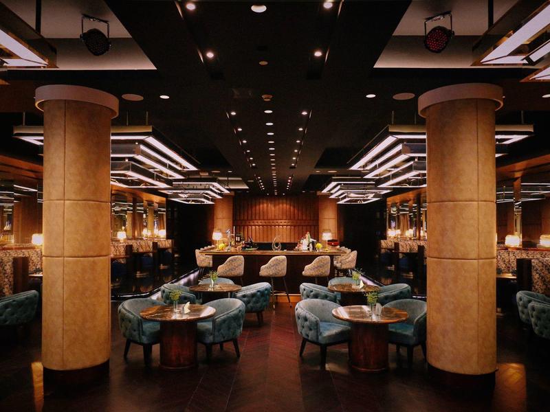 Elegant hotel restaurant with round tables, columns, and cozy lighting.