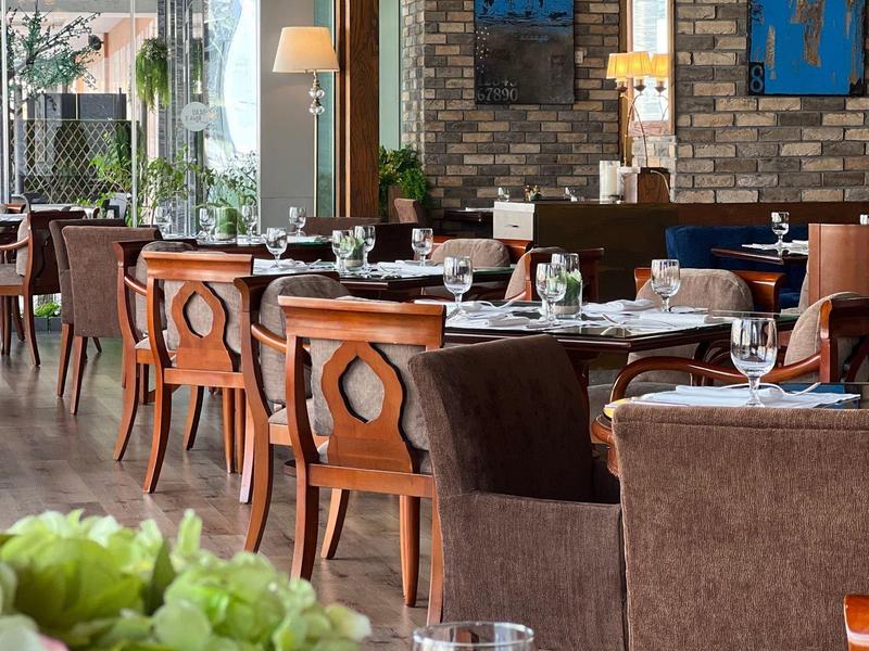 Modern restaurant with wooden tables, comfortable chairs, and wall decorations.