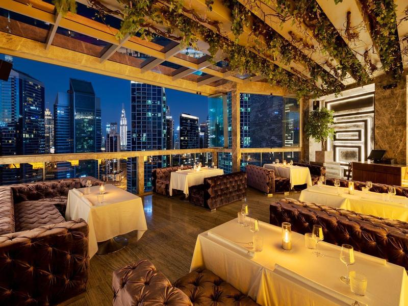 Elegant restaurant with set tables and city view at night.
