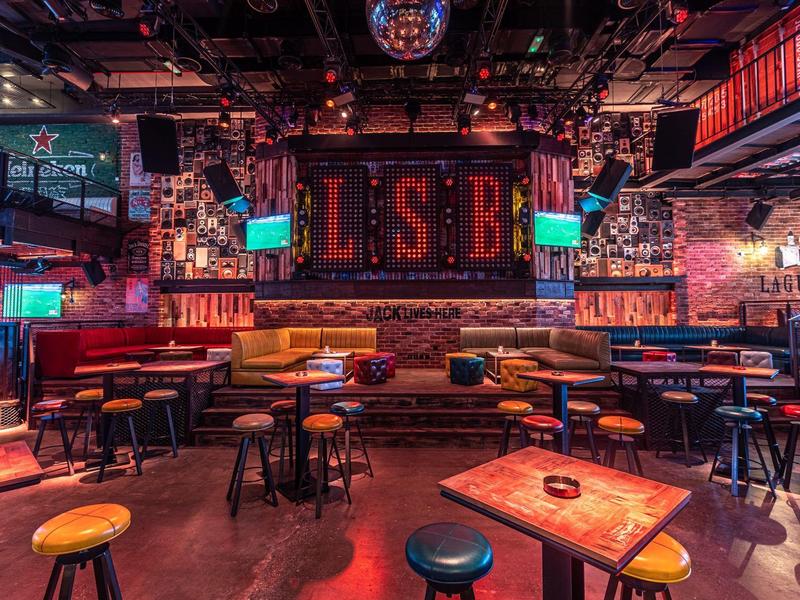Colorful bar with stools, tables, and vibrant lighting indoors.
