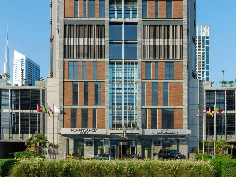 Modern multi-story office building with glass and brick facade and flags at the entrance.