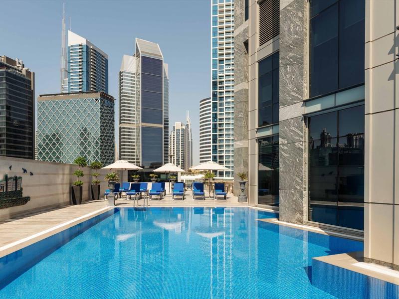 Modern outdoor rooftop pool with view of high-rise buildings in the city