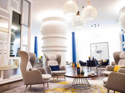 Modernes Hotelzimmer mit stilvollen Sesseln, Marmortischen und großen Säulen.