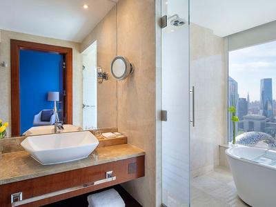 Modernes Hotelbad mit Waschbecken, Dusche und freistehender Badewanne mit Stadtblick.