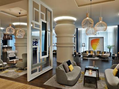 Modern eingerichteter Hotel-Loungebereich mit gemütlichen Sesseln, Tischen und dekorativen Lampen.
