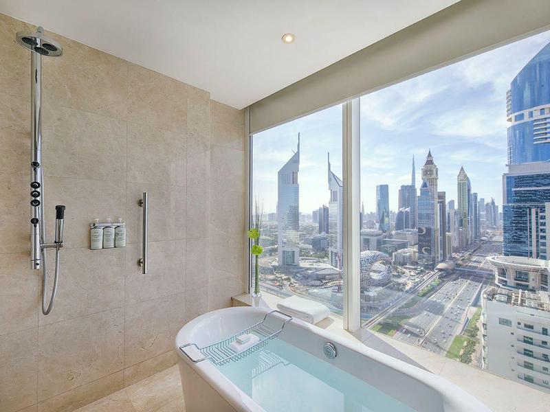 Moderne Badewanne mit großer Glasfront und Blick auf die urbanen Wolkenkratzer.