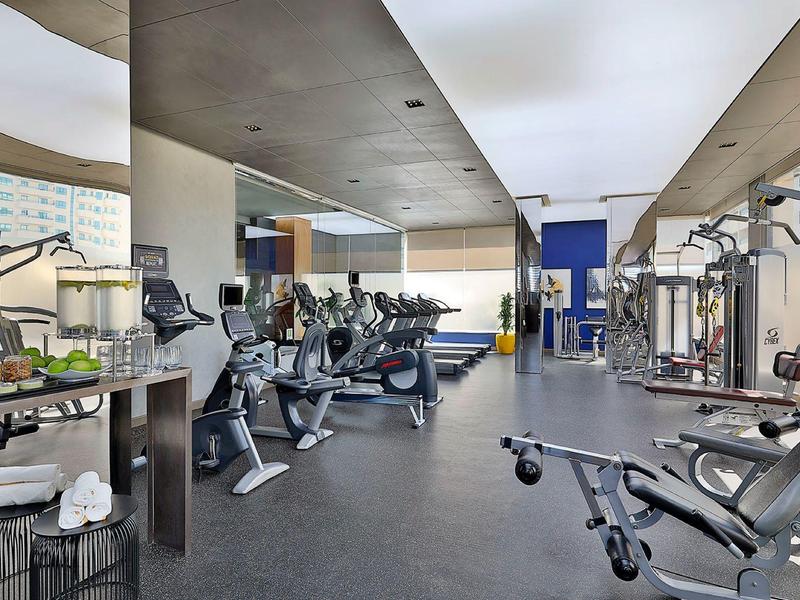 Moderner Fitnessraum mit Cardio- und Kraftgeräten in einem Hotel mit Blick auf die Stadt