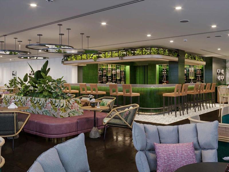Moderner Hotel-Salon mit grünem Barbereich, gemütlichen Sitzgruppen und Pflanzen.