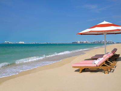 Spiaggia con lettini e ombrellone vicino al mare sotto un cielo sereno