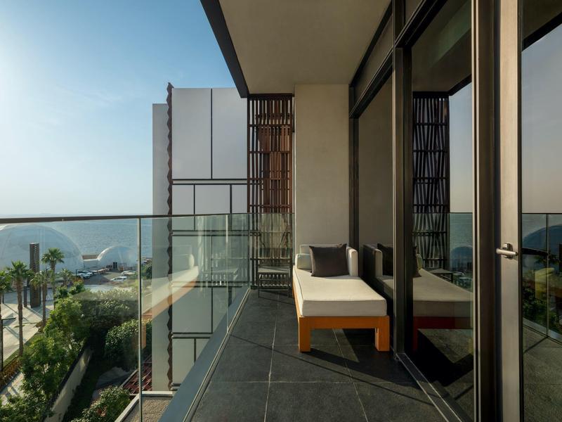 Modern balkon met glazen balustrade met uitzicht op zee en palmbomen.