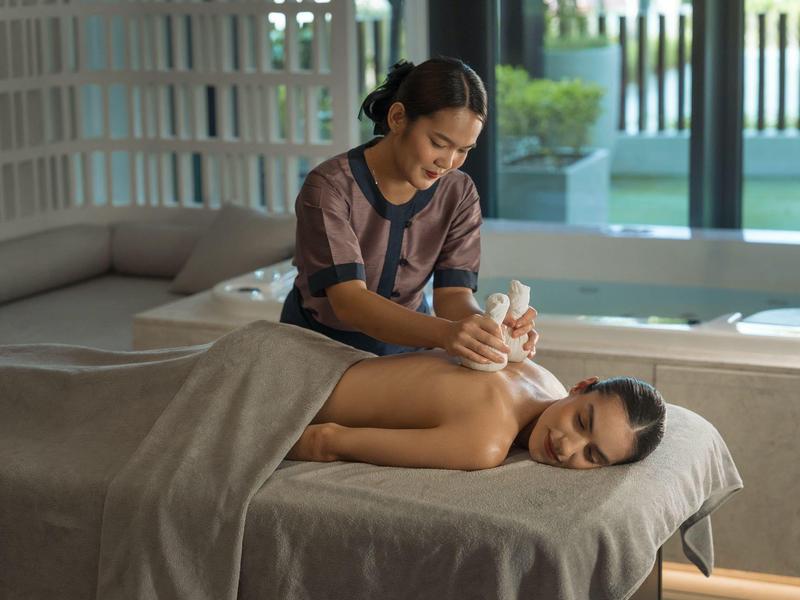 Een vrouw krijgt een aromatherapiemassage in een moderne wellnessruimte.