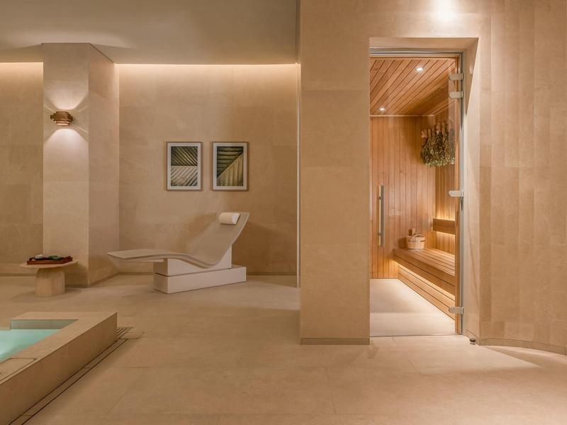 Moderne wellnessruimte met sauna, ligstoel en ontspannend zwembad in warme tinten.