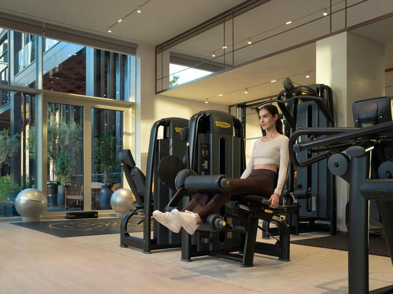 Vrouw traint op fitnessapparaat in een moderne sportschool met grote ramen.