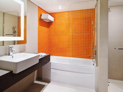 Bagno moderno con parete piastrellata arancione, vasca da bagno e lavabo.