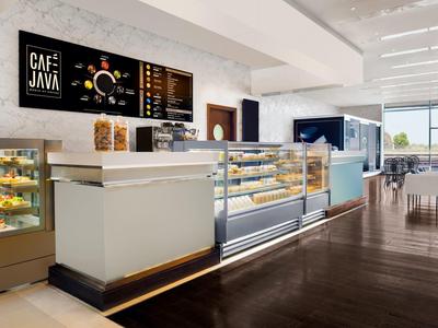 Caffetteria moderna con interno luminoso e grande bancone con pasticceria e macchina da caffè