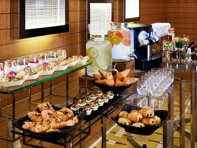 Buffet con pasticcini, snack, bevande e bicchieri in un interno moderno di un hotel.