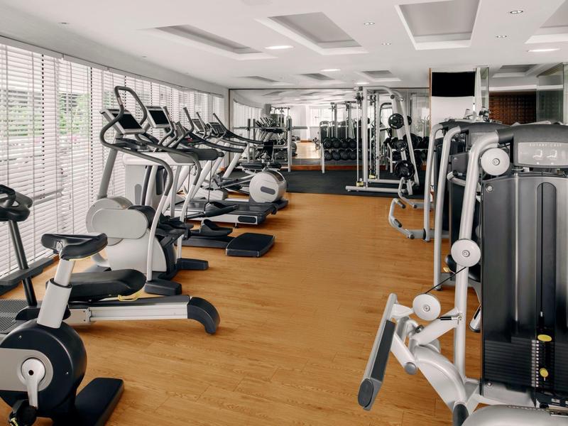 Palestra luminosa con pavimento in legno e varie attrezzature per l'allenamento e cardio.