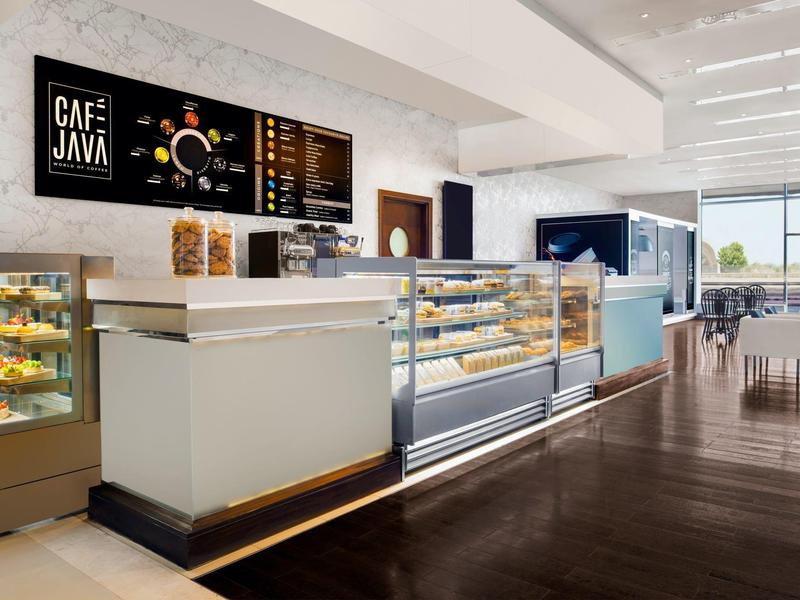 Caffetteria moderna con interno luminoso e grande bancone con pasticceria e macchina da caffè