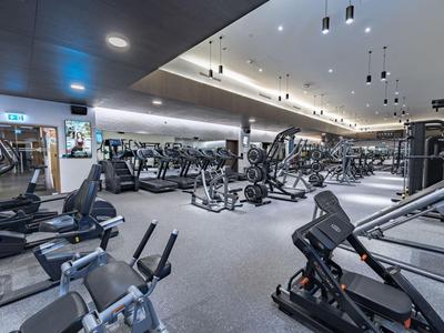 Velká posilovna s moderním zařízením a jasným osvětlením.