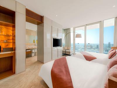 Moderne hotelkamer met twee bedden, grote ramen en uitzicht op de stad.