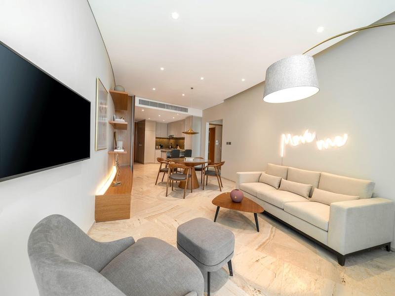 Moderne woonkamer met bank, tv, eettafel en open keuken in een helder ontwerp.