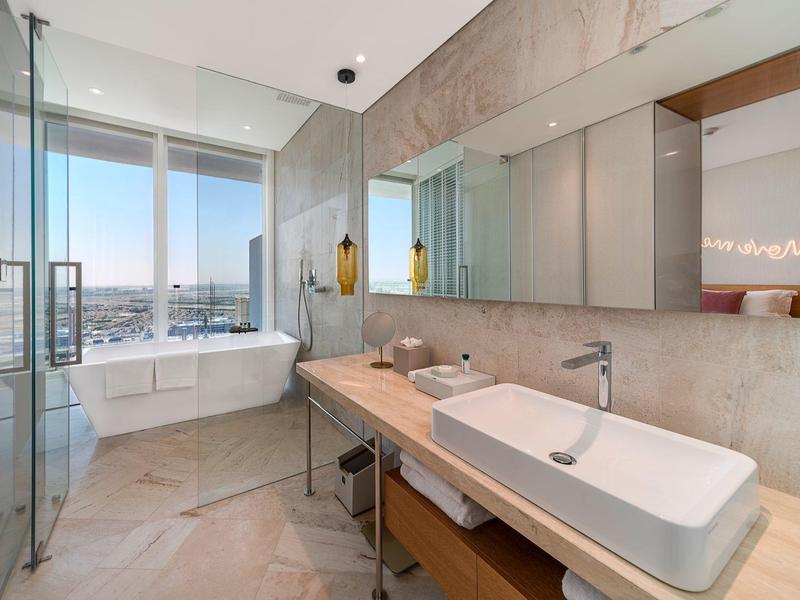 Moderne badkamer met groot bad, douche en dubbele wastafels onder een grote spiegel.