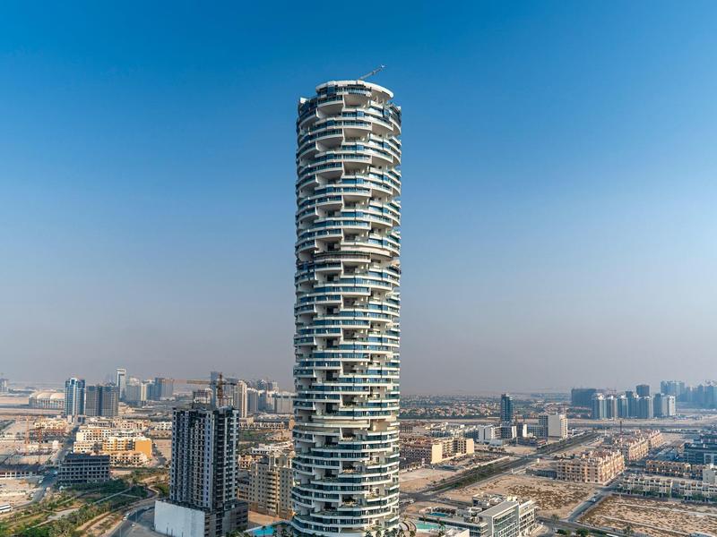 Moderne hotelbar met ronde houten tafels en blauwe fluwelen stoelen in warm verlichte ruimte.