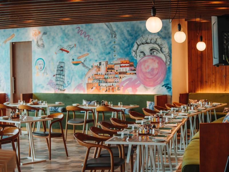 Modern restaurant met kleurrijk muurschildering en stijlvolle houten meubels.